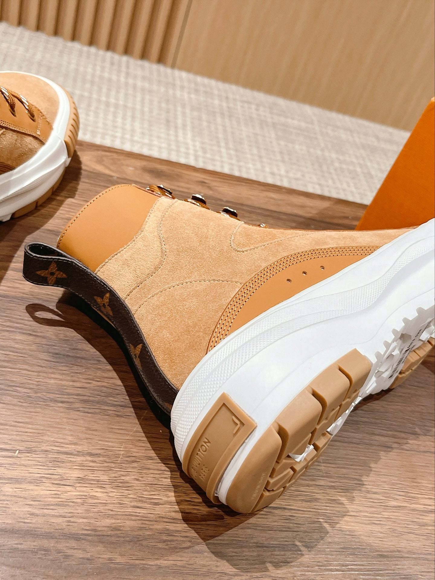 Tan Louis Vuitton high-top sneaker with black heel patch, white sole, and lace-up design