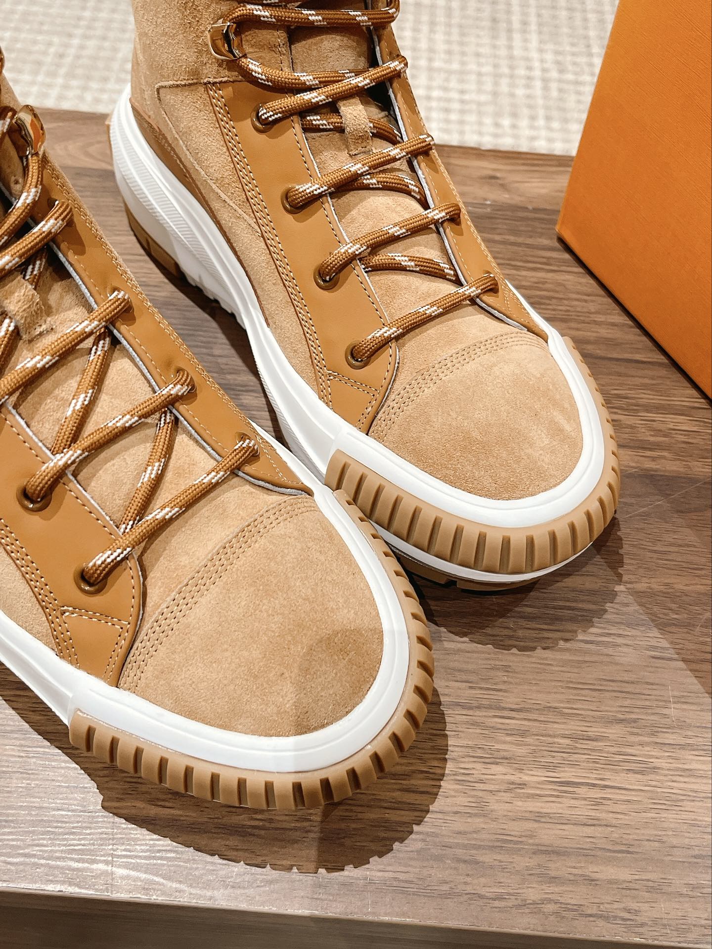 Pair of tan Louis Vuitton high-top sneakers with lace-up front and white rubber soles