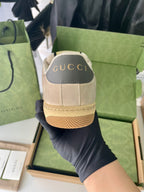 Cream suede sneakers with 'GUCCI' heel patch and textured tan sole edge.