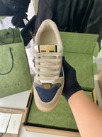 Cream suede lace-up sneakers with Gucci heel emblem and blue side panel.