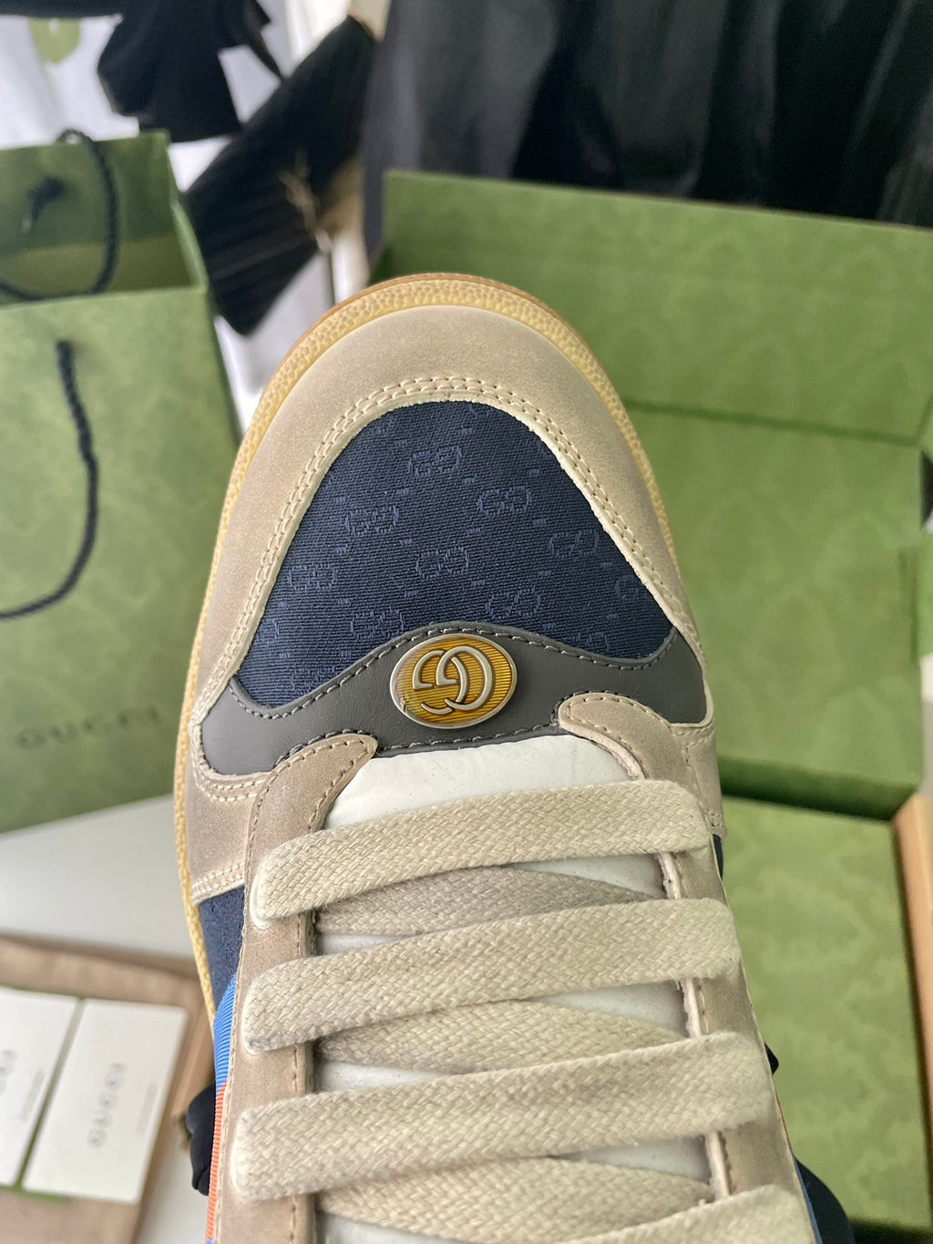 Cream suede sneakers toe view with Gucci logo plaque on heel collar.