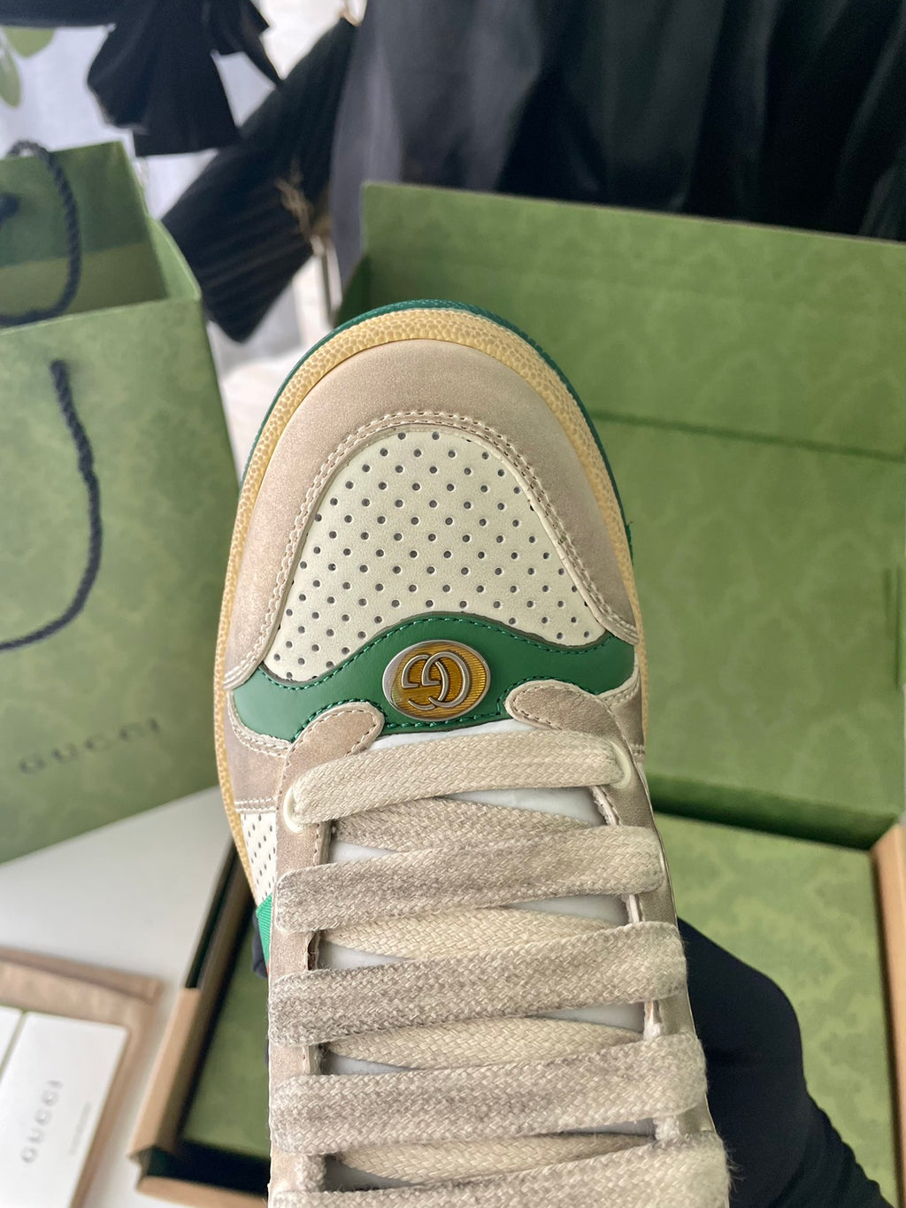 Gucci unisex sneaker close-up, perforated beige toe with green crest emblem