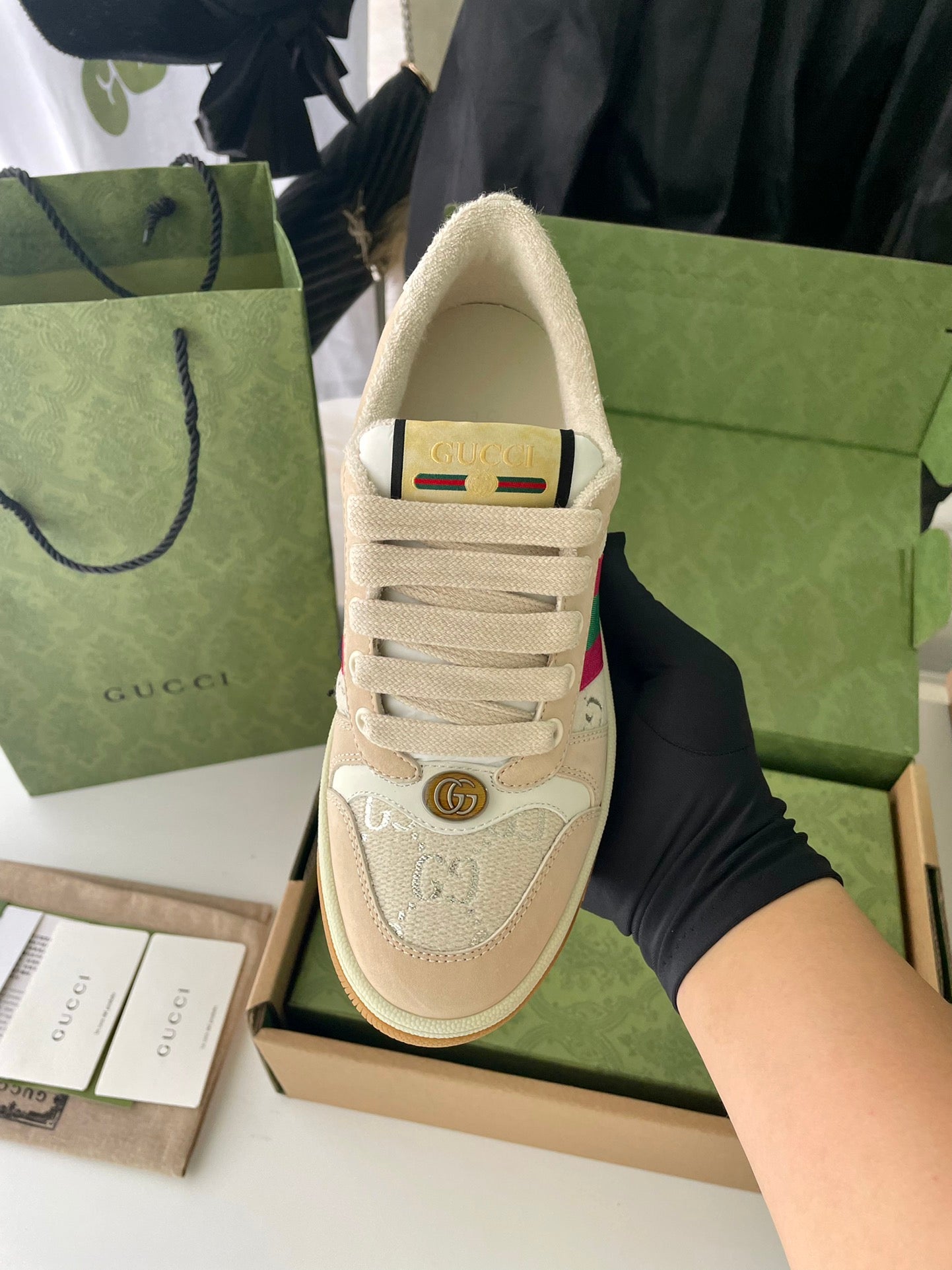 Beige lace-up low-top sneaker showing tongue and heel patch with colorful stripe