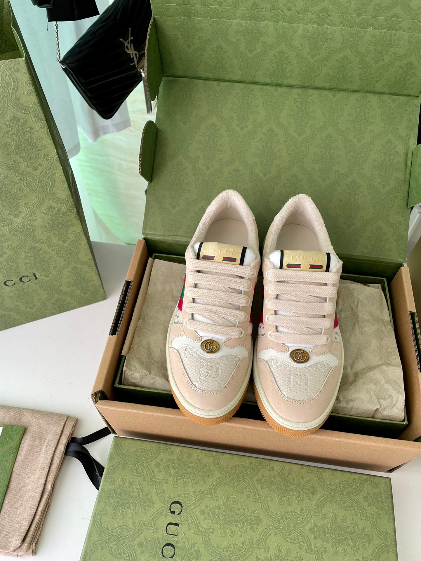 Beige lace-up low-top sneakers with side stripe and embossed emblem in a box