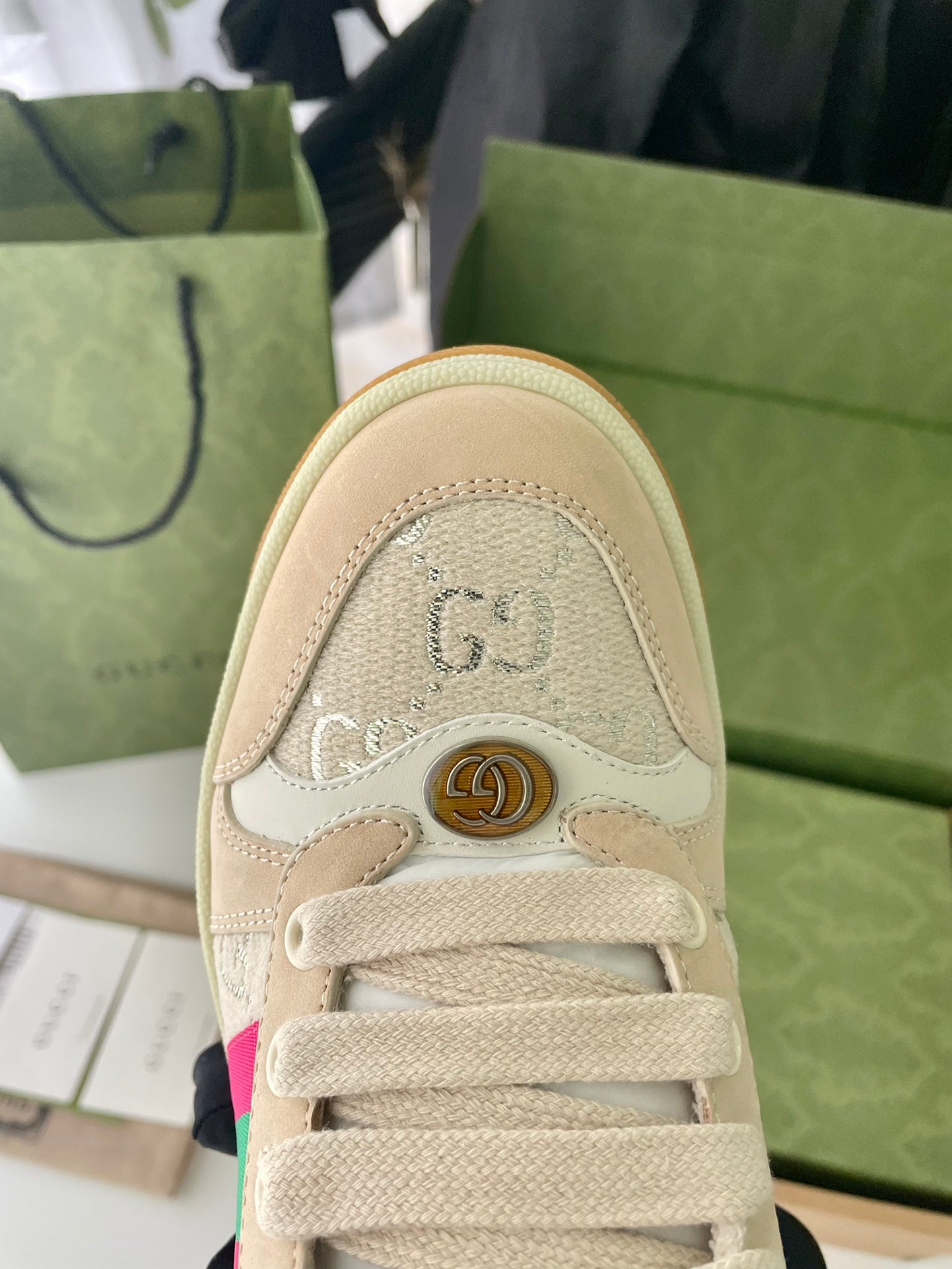 Beige sneaker close-up of lace area with embossed emblem and trim stitching