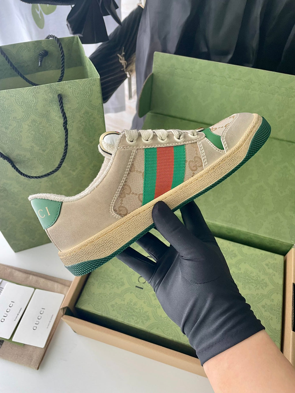 Beige low-top sneakers with green red stripe on side and lace-up front.