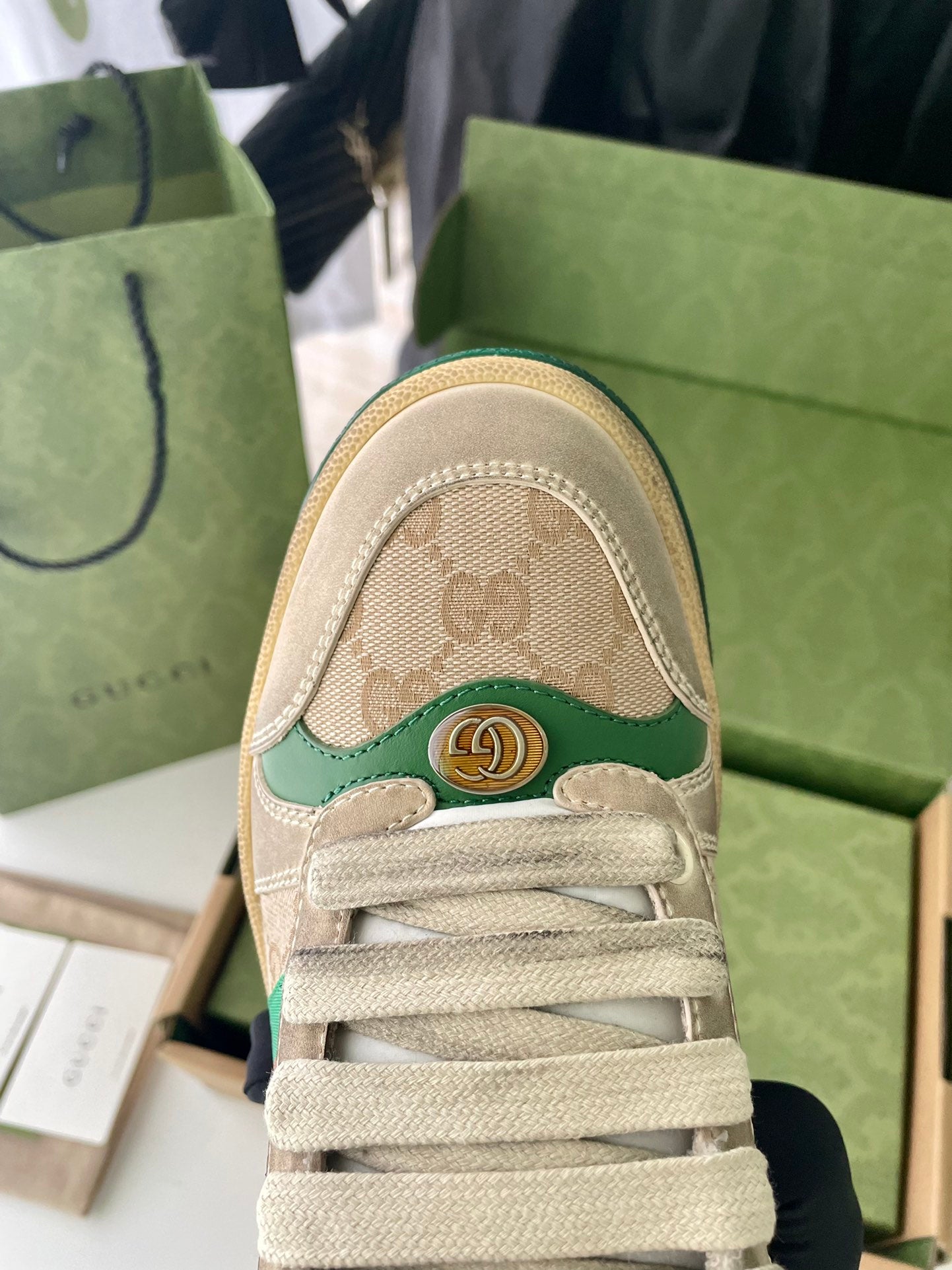 Beige sneaker toe cap with GG logo pattern, green trim, and lace-up front.