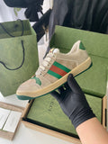 Beige low-top sneakers with green red stripe detail and textured rubber sole.