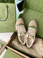 Pair of beige low-top sneakers with green red stripe Web detail and lace-up uppers.