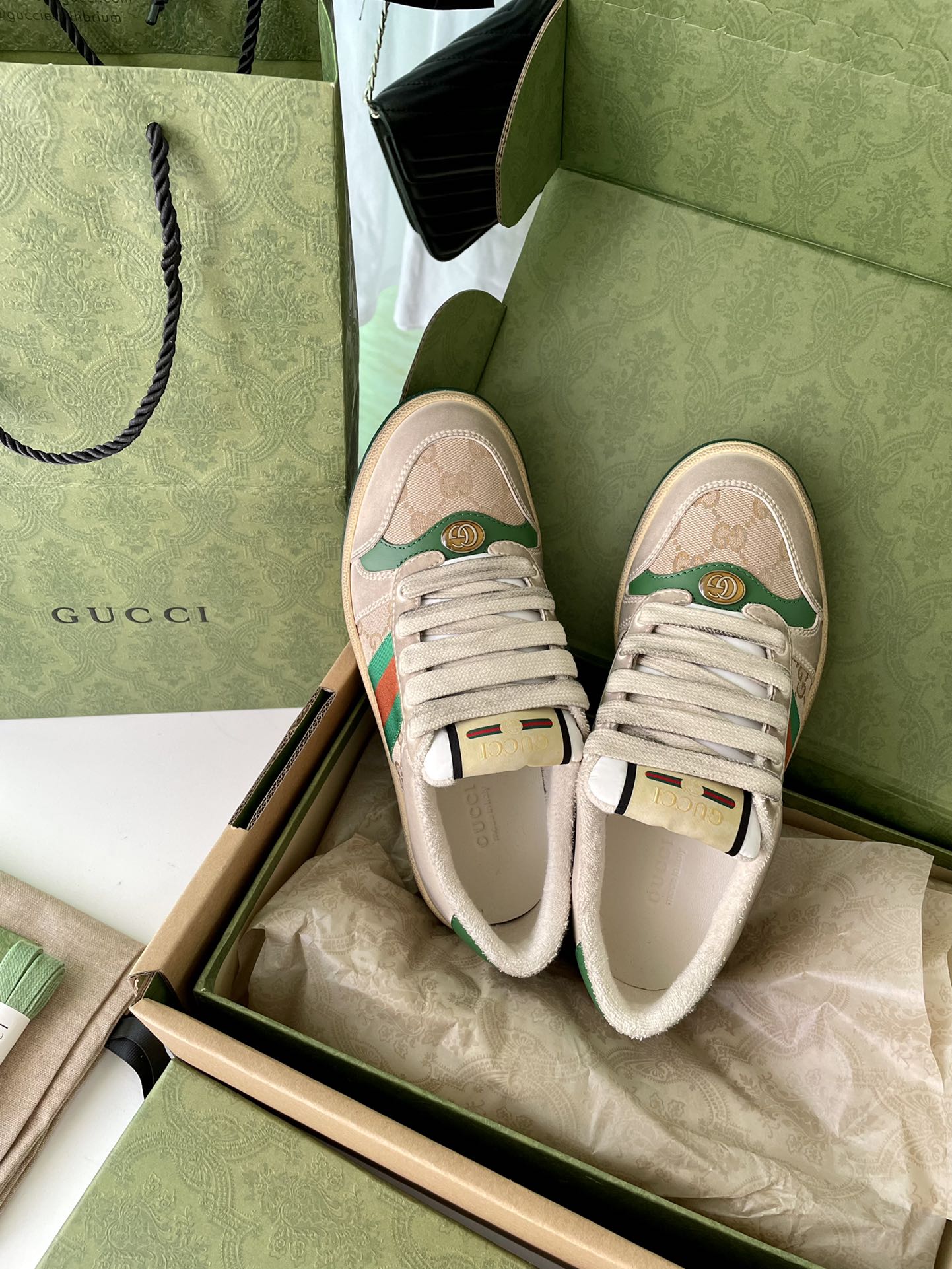Pair of beige low-top sneakers with green red stripe Web detail and lace-up uppers.