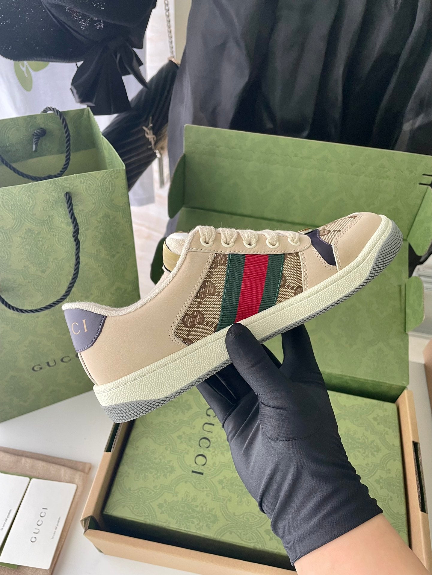 Gucci sneaker side view with beige canvas, red/green Web stripe, white rubber sole.