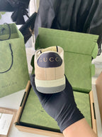 Gucci sneaker heel and back view with beige leather upper and tread sole.