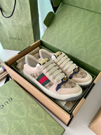 Gucci sneakers pair with beige GG canvas, red/green Web stripe, gold emblem, lace-up.