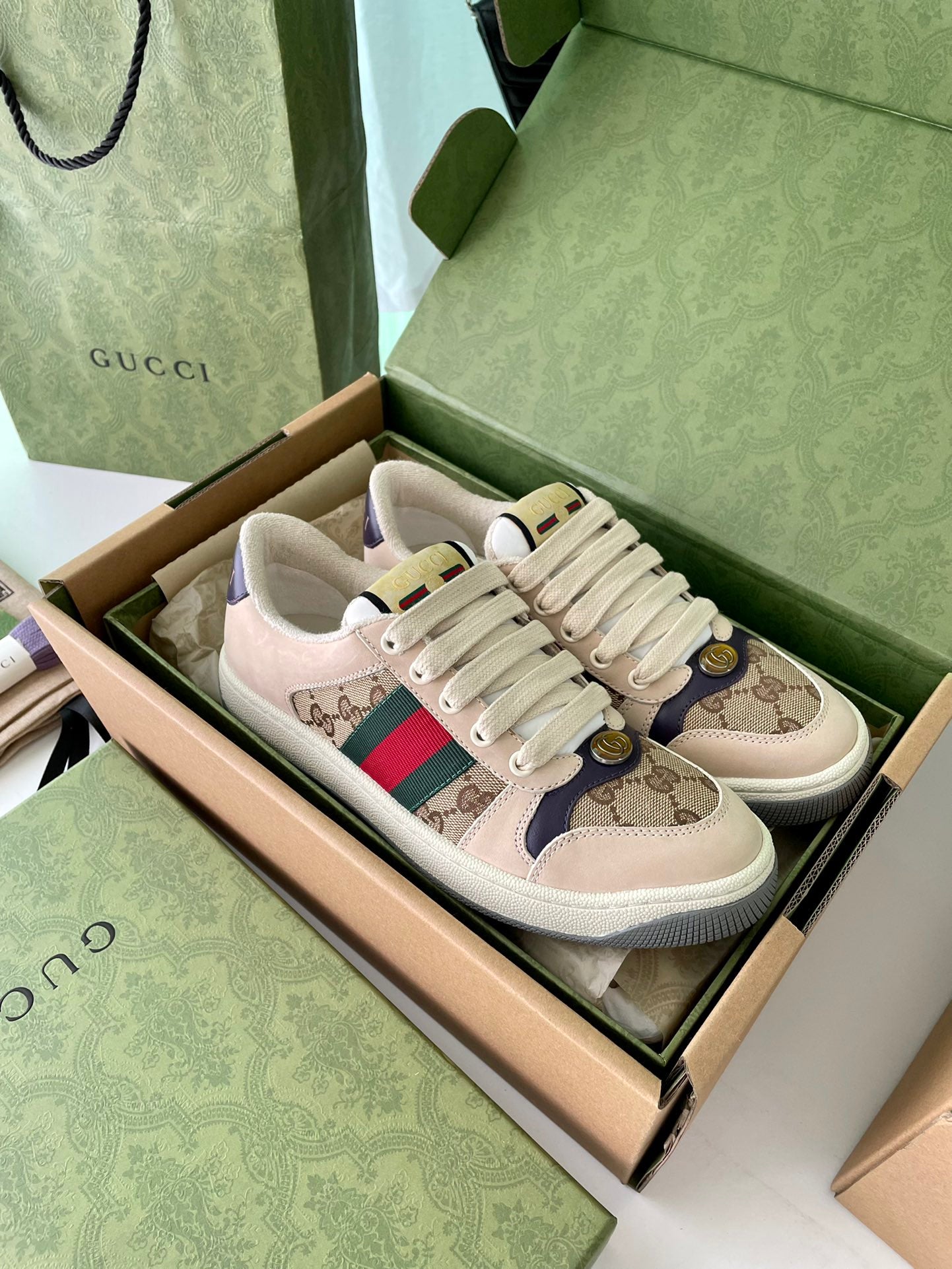 Gucci sneakers pair with beige GG canvas, red/green Web stripe, gold emblem, lace-up.