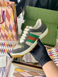 Gucci unisex low-top sneakers in dark gray with green/red stripe and white laces.