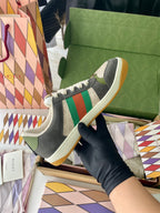 Gucci unisex low-top sneakers on box: dark gray uppers with green/red web stripe.