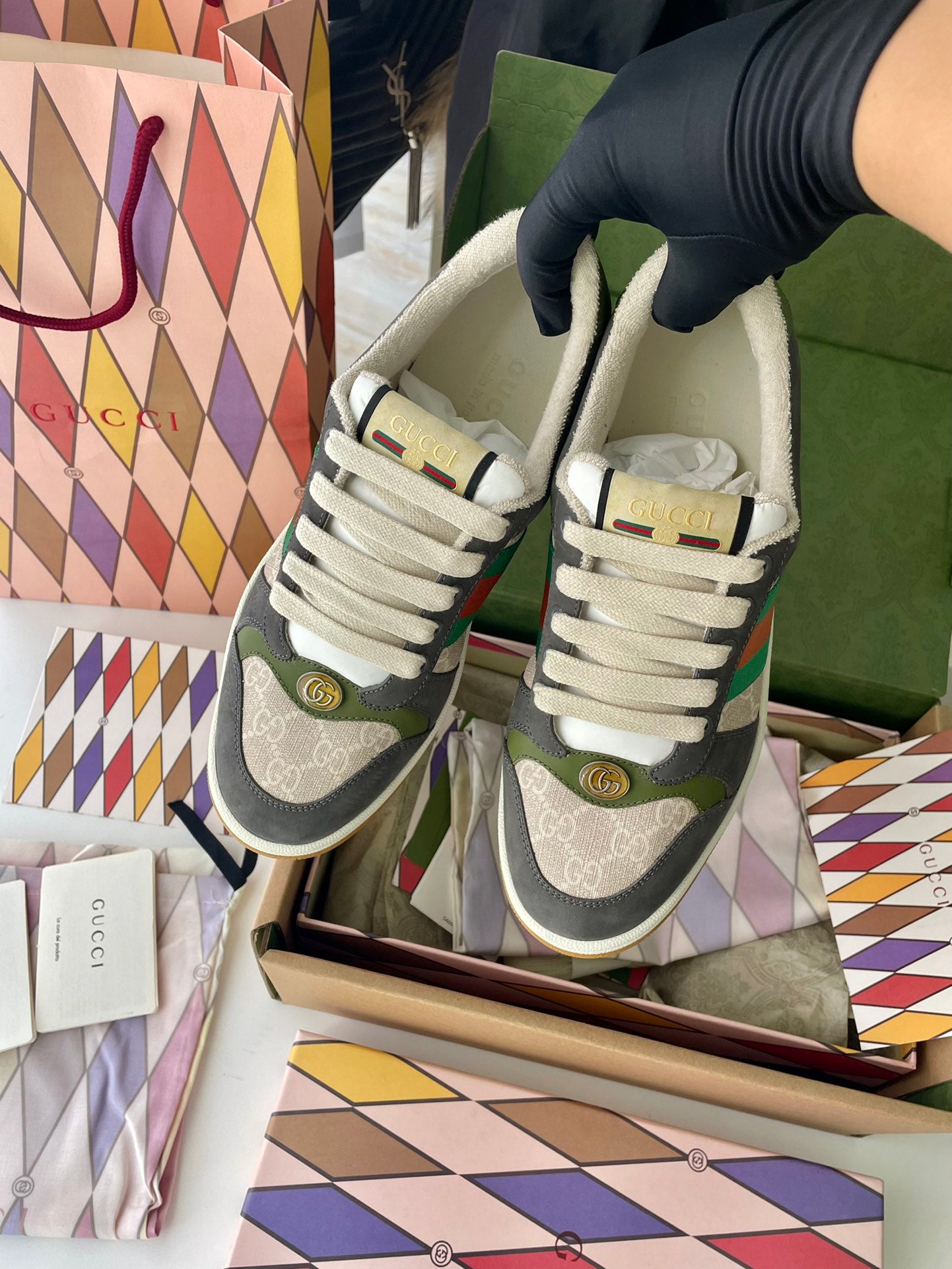 Pair of Gucci unisex low-top sneakers in box: dark gray, white laces, green/red stripe.