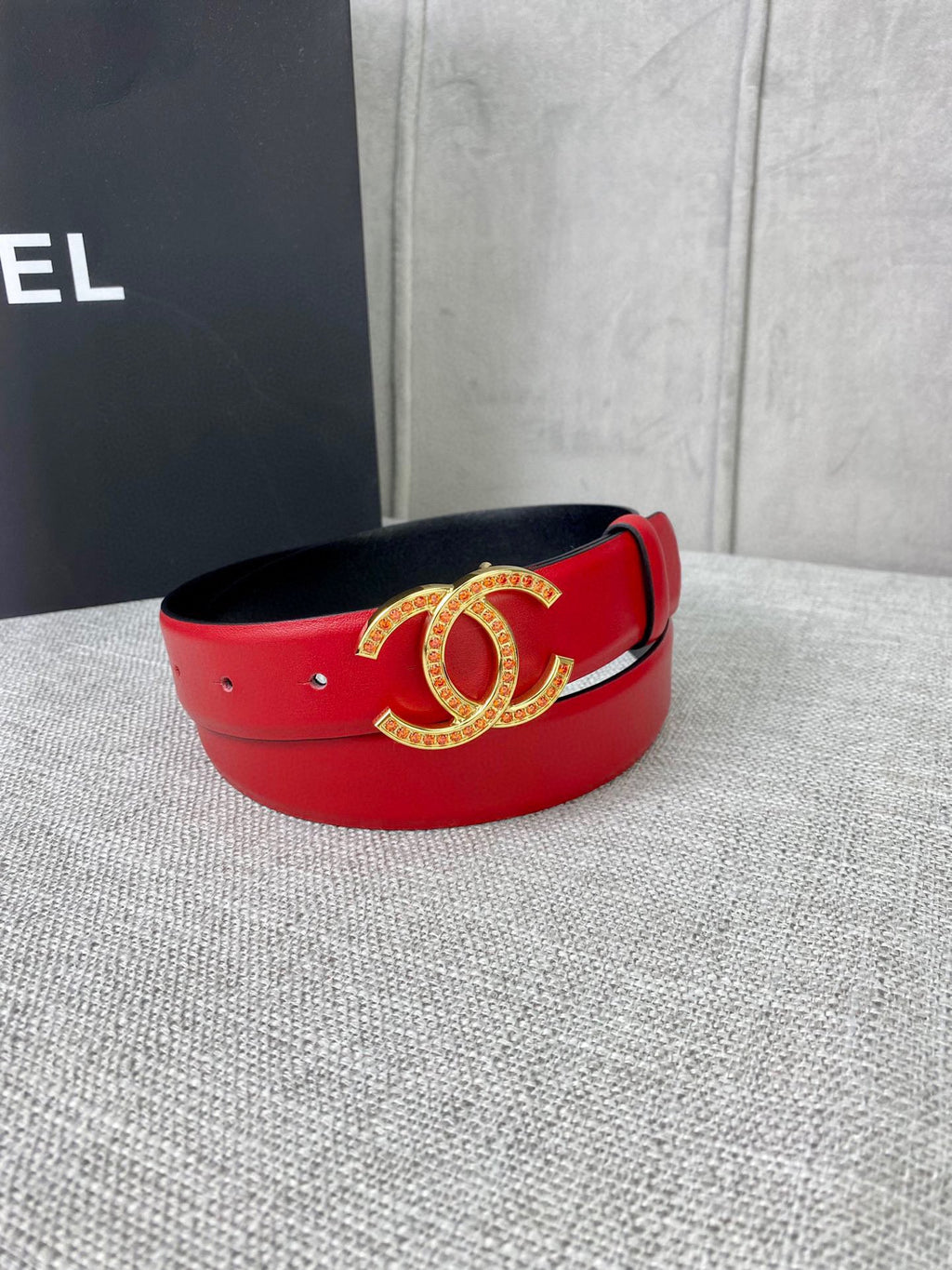 Red leather belt with gold-tone CC logo buckle, front view with curved band