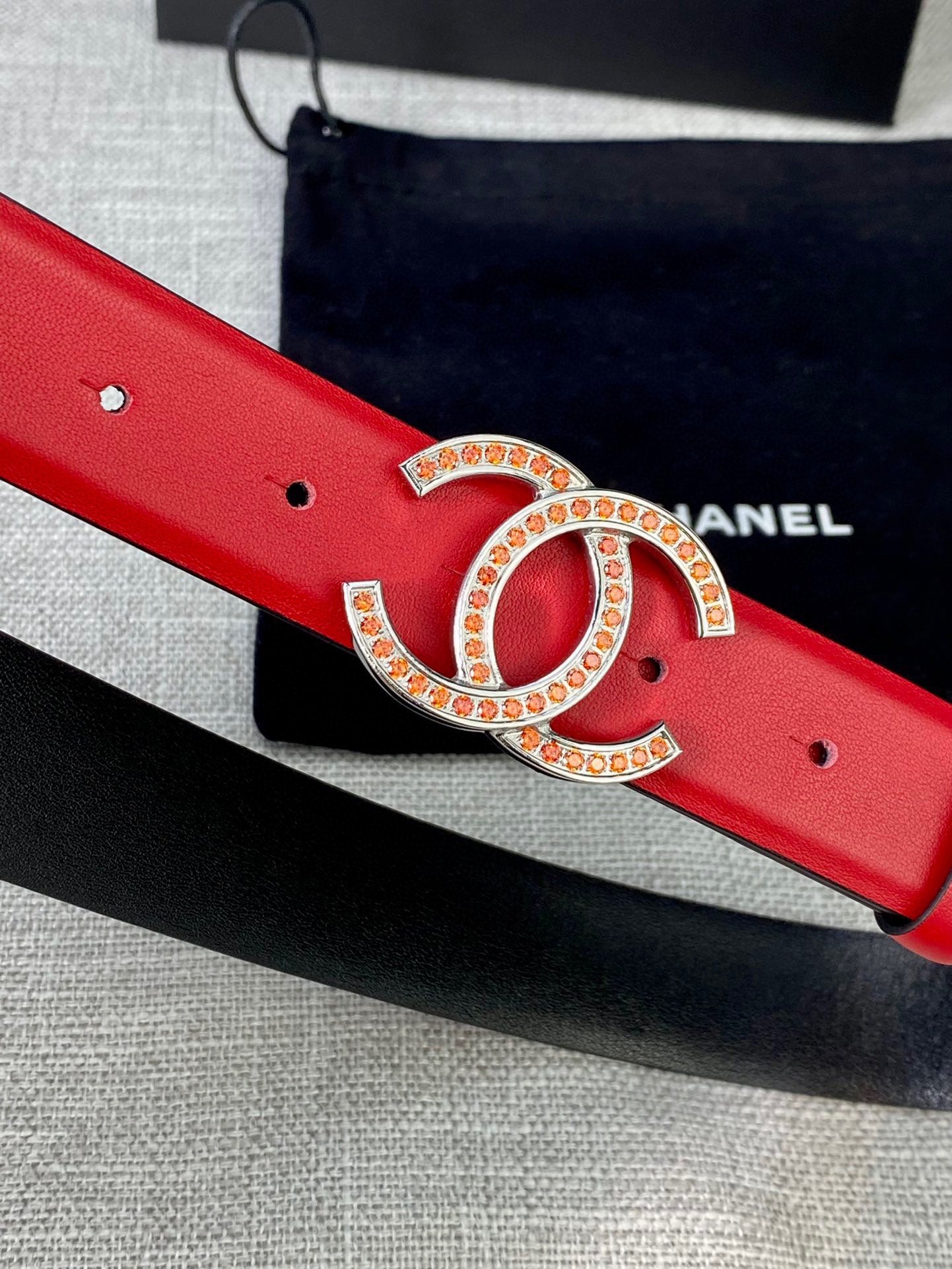 Red leather belt with large gold-tone CC logo buckle and stud holes