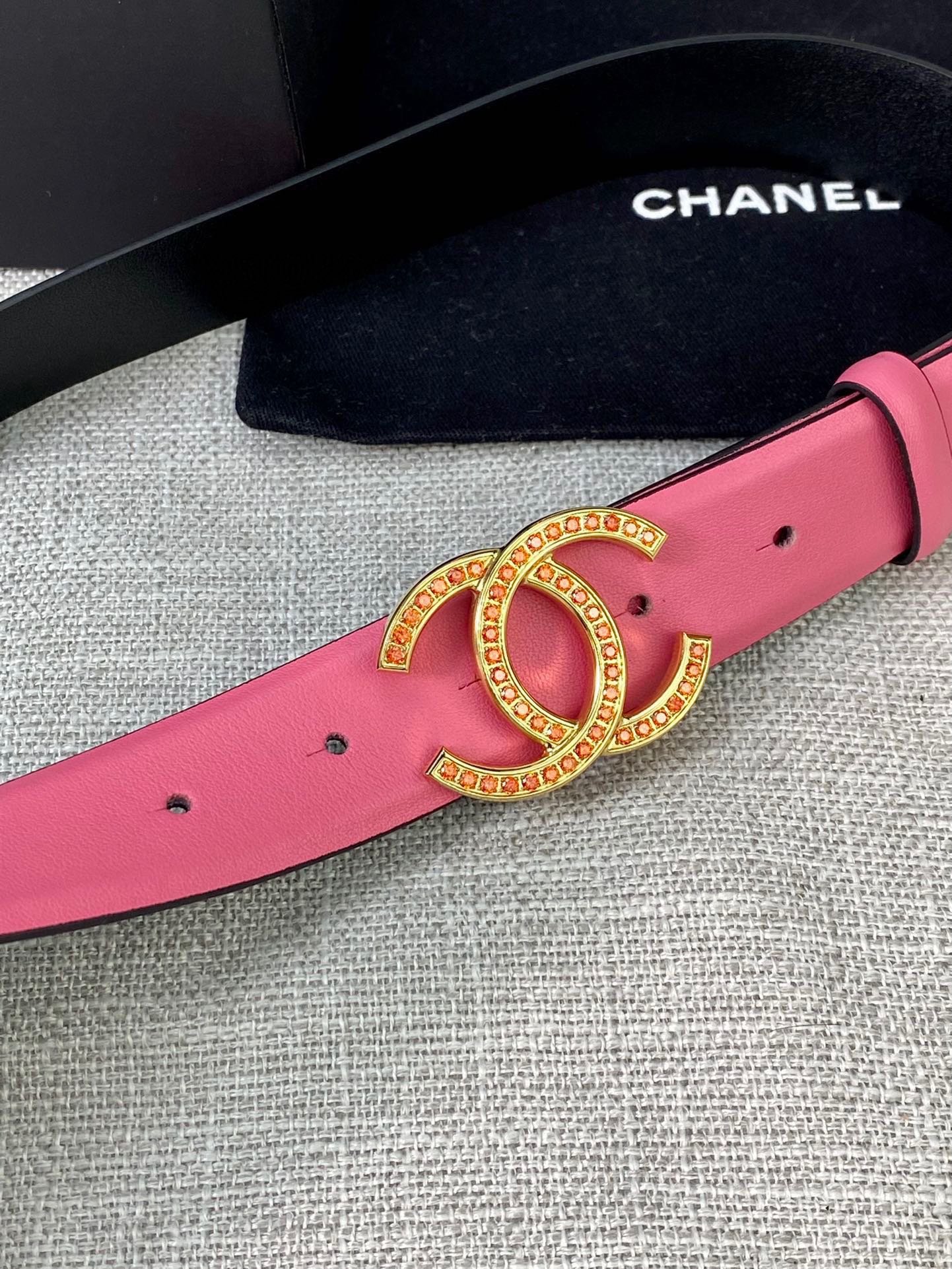 Pink leather belt with gold-tone CC logo buckle, close-up on gold hardware
