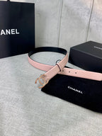 Light pink leather belt with gold logo buckle, coiled in front of gift box