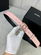 Light pink leather belt with gold logo buckle, front view on black box
