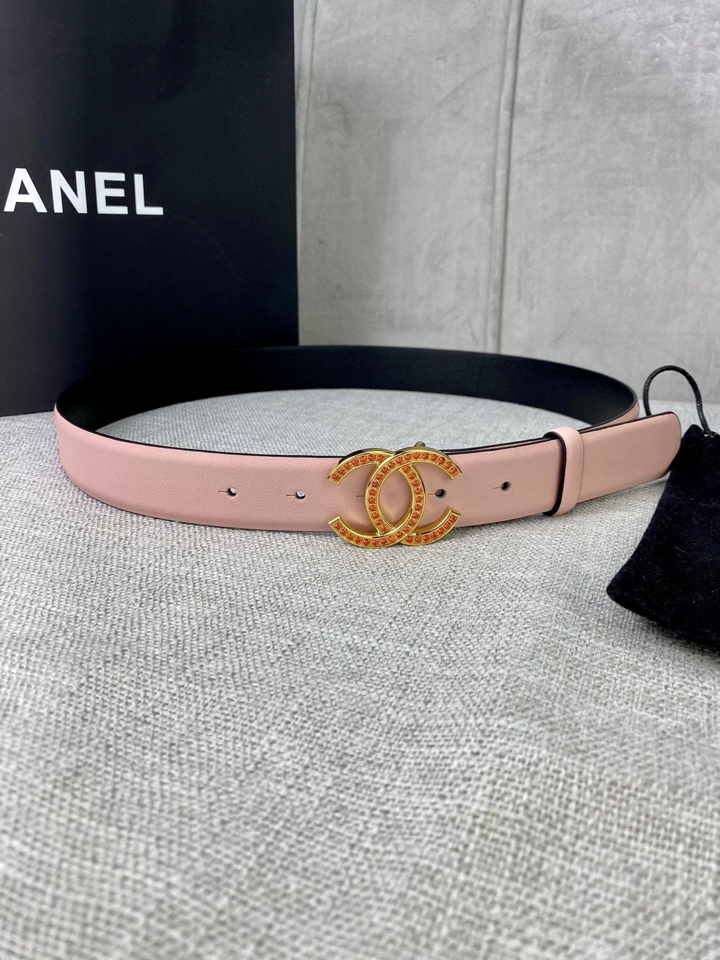 Light pink leather belt with gold logo buckle and rhinestone border