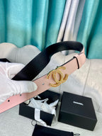 Light pink leather belt with gold logo buckle, held by white-gloved hands