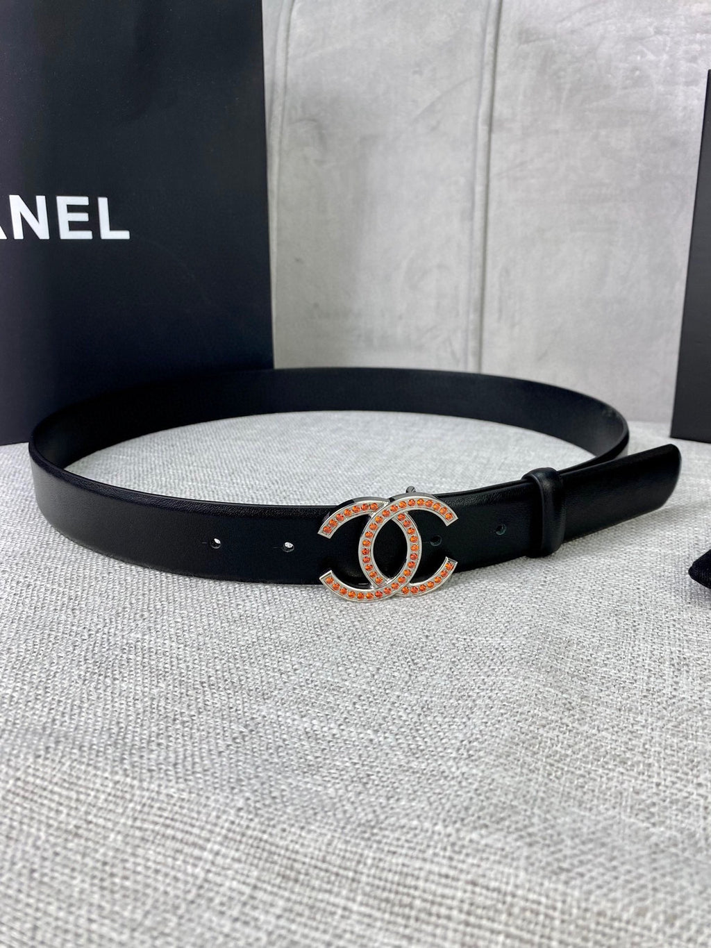 Black leather belt with gold-and-red CC buckle and metal eyelets