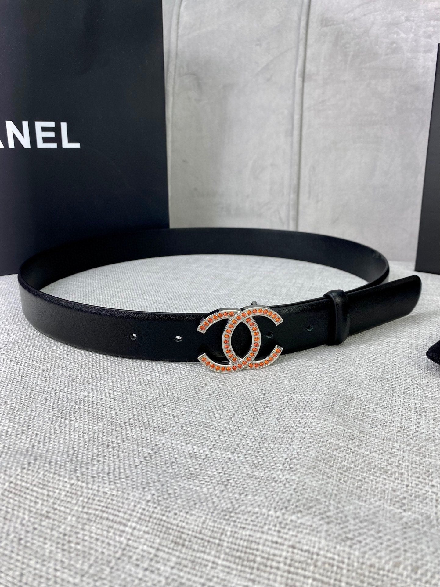 Black leather belt with gold-and-red CC buckle and metal eyelets