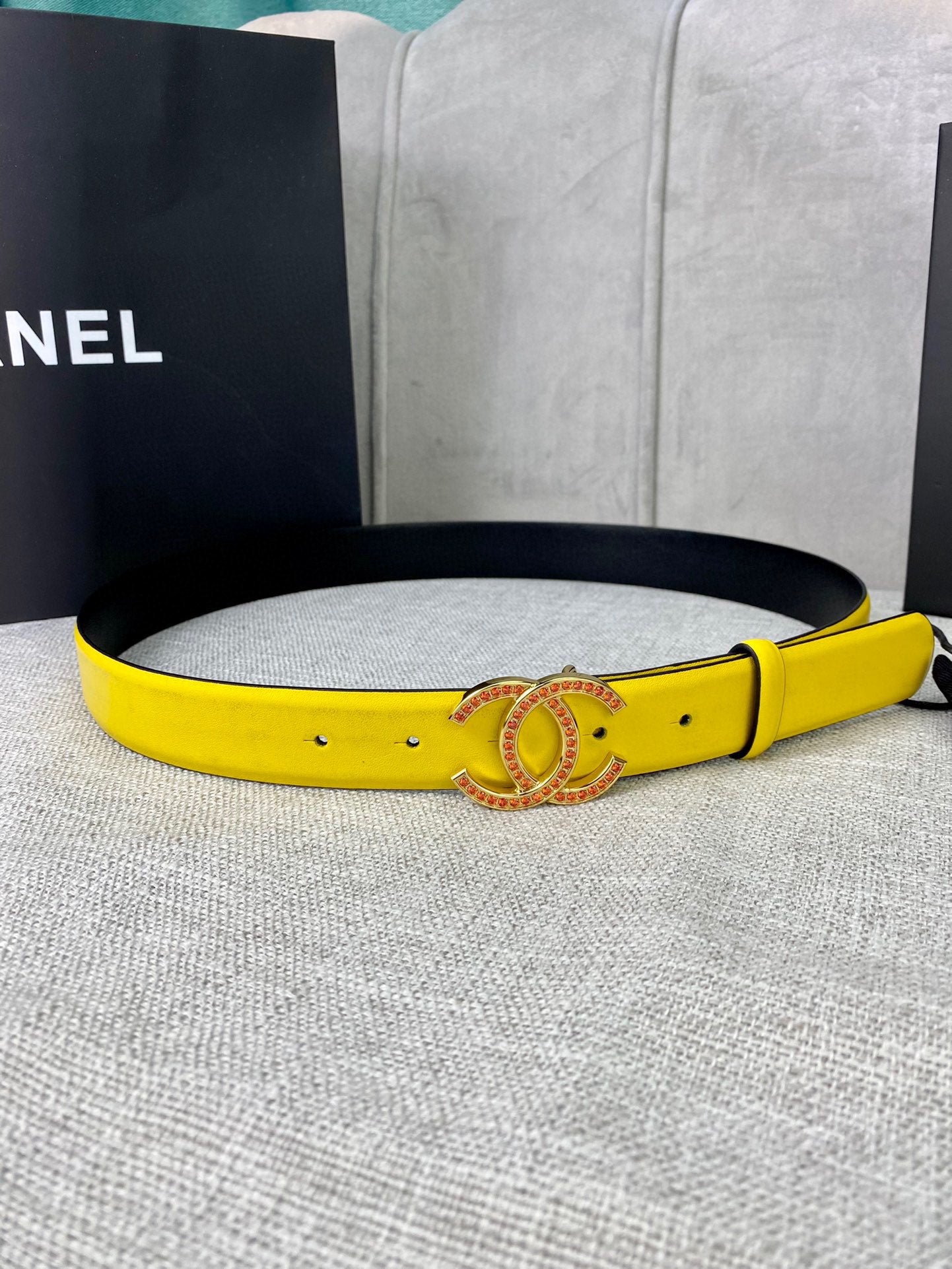 Yellow leather belt with black underside and gold-tone logo buckle