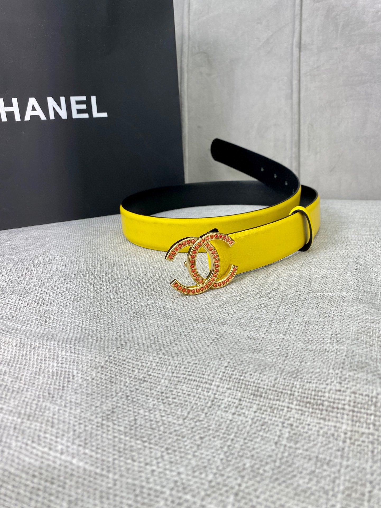 Yellow belt with gold-tone logo buckle, side view with black inner edge