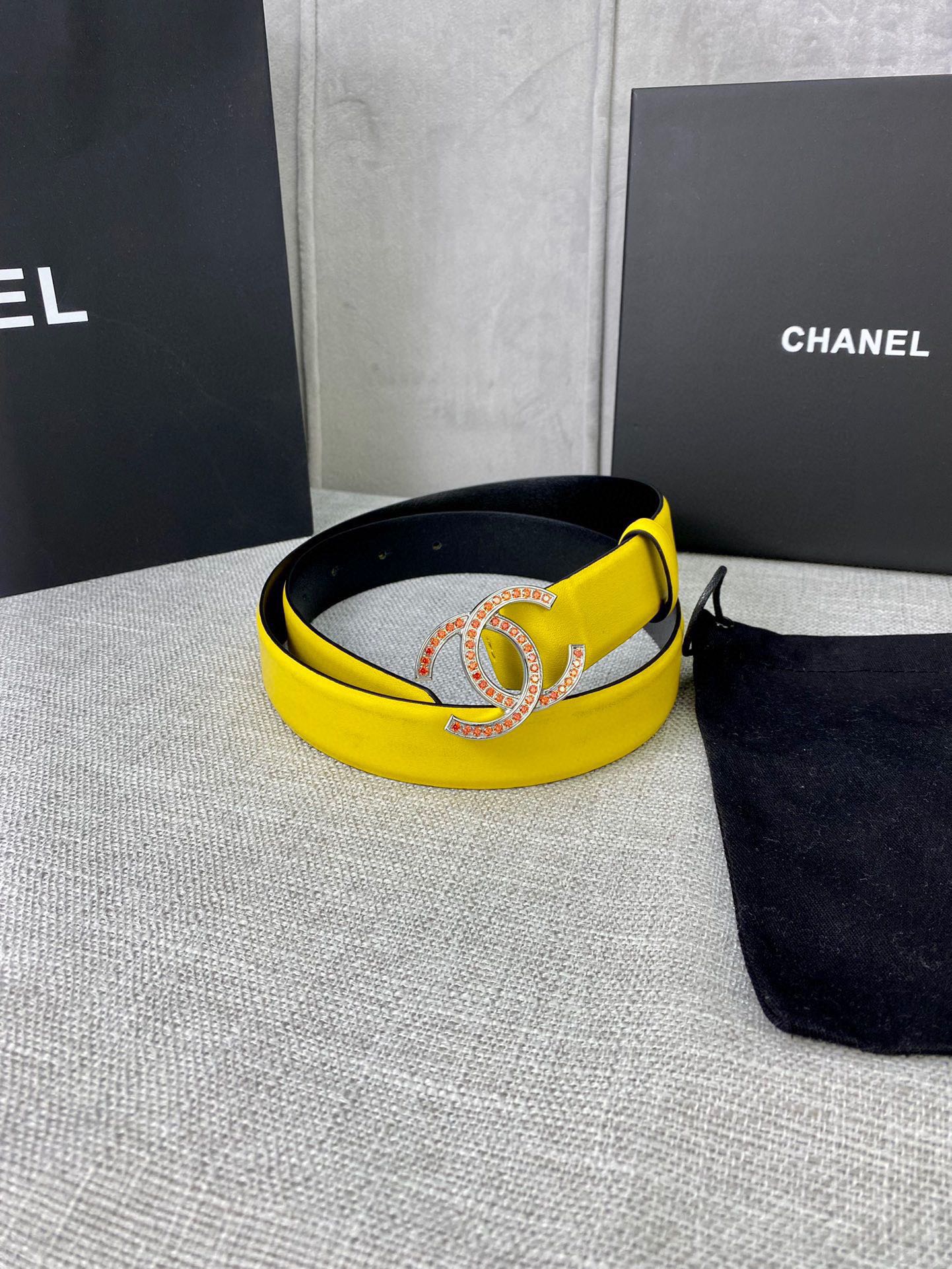 Yellow leather belt with gold-tone logo buckle, laid flat