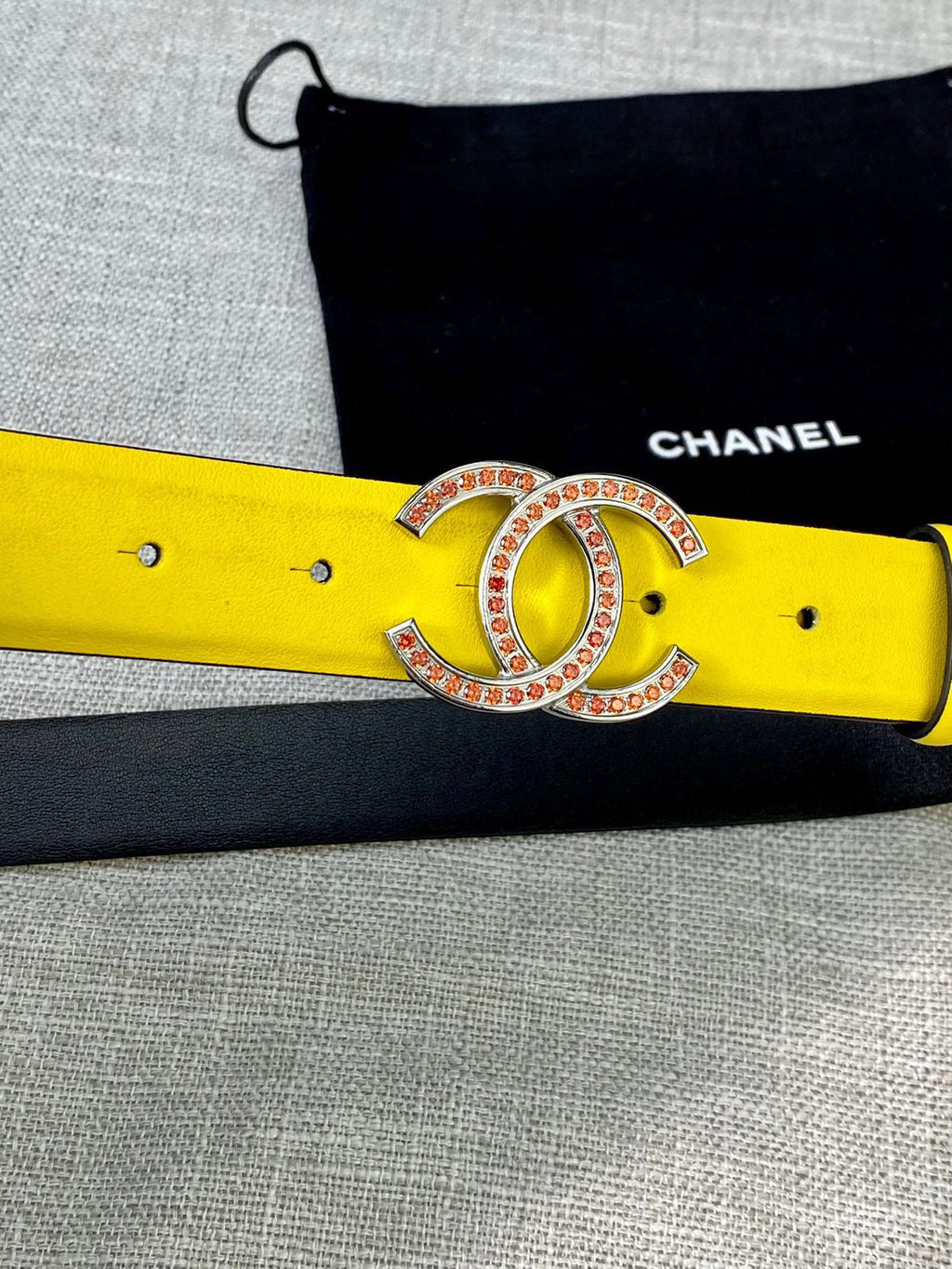 Yellow belt close-up with gold-tone logo buckle and rhinestone trim