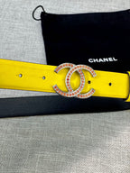 Yellow belt close-up with gold-tone logo buckle and rhinestone trim