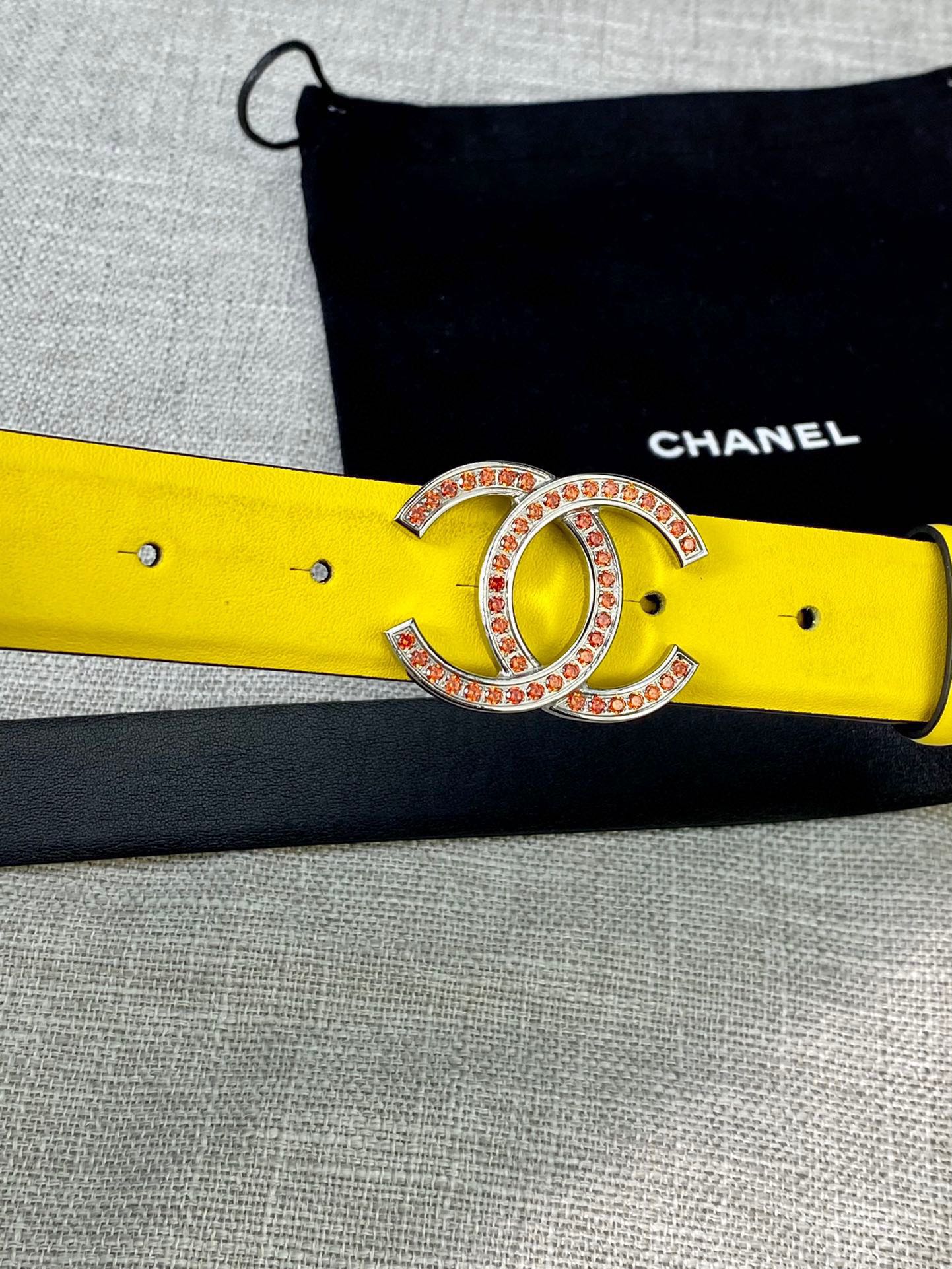 Yellow belt close-up with gold-tone logo buckle and rhinestone trim