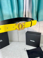 Yellow leather belt with gold-tone logo buckle, resting beside a black pouch
