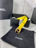 Yellow leather belt with gold-tone logo buckle, shown with black dust bag