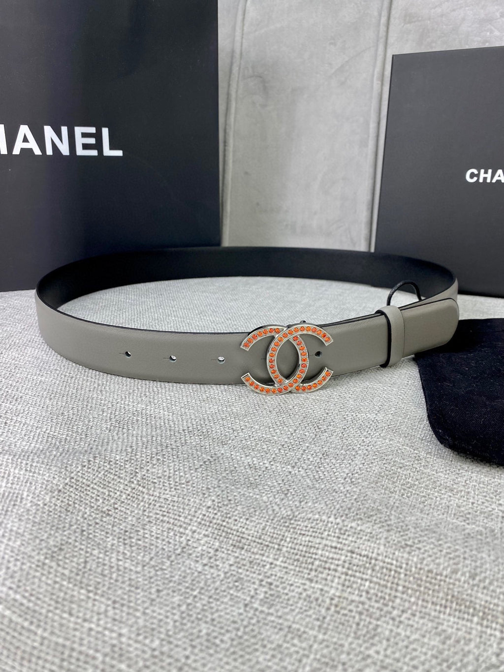 Light gray leather belt with oval CC buckle in gold and orange enamel