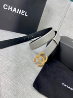 Light gray belt with oval CC buckle, laid over Chanel dust bag