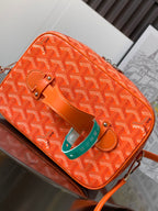 Small orange patterned bag with flap, shoulder strap, and turquoise hanging tag