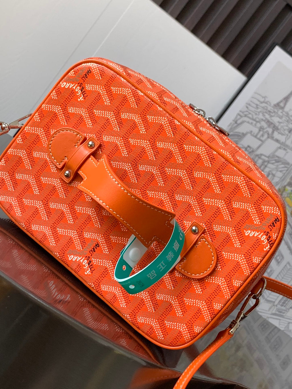 Goyard bag exterior in bright orange with monogram pattern and top handle