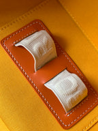 Orange fabric-lined interior pocket with stitched leather trim and snap strap tabs