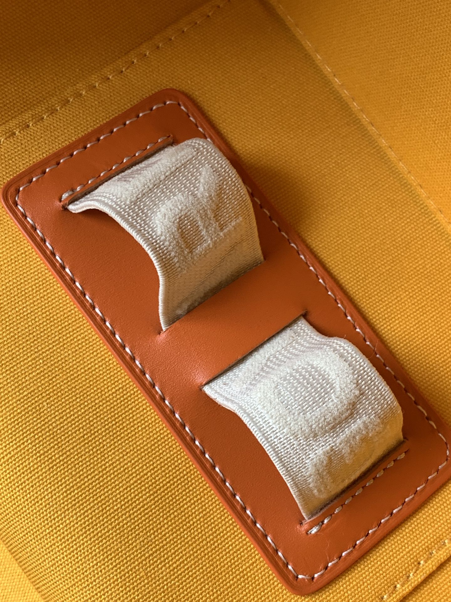 Orange fabric-lined interior pocket with stitched leather trim and snap strap tabs