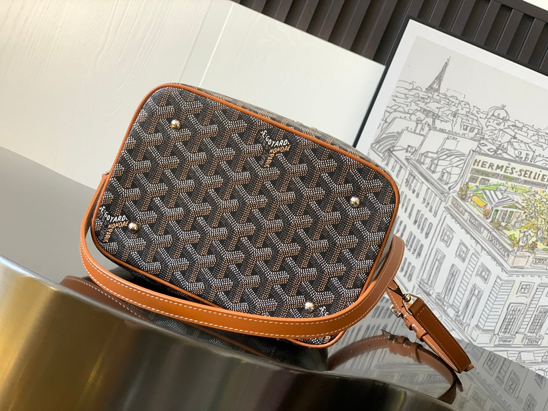 Small crossbody bag with Goyard-print canvas exterior, tan piping, and adjustable leather strap.