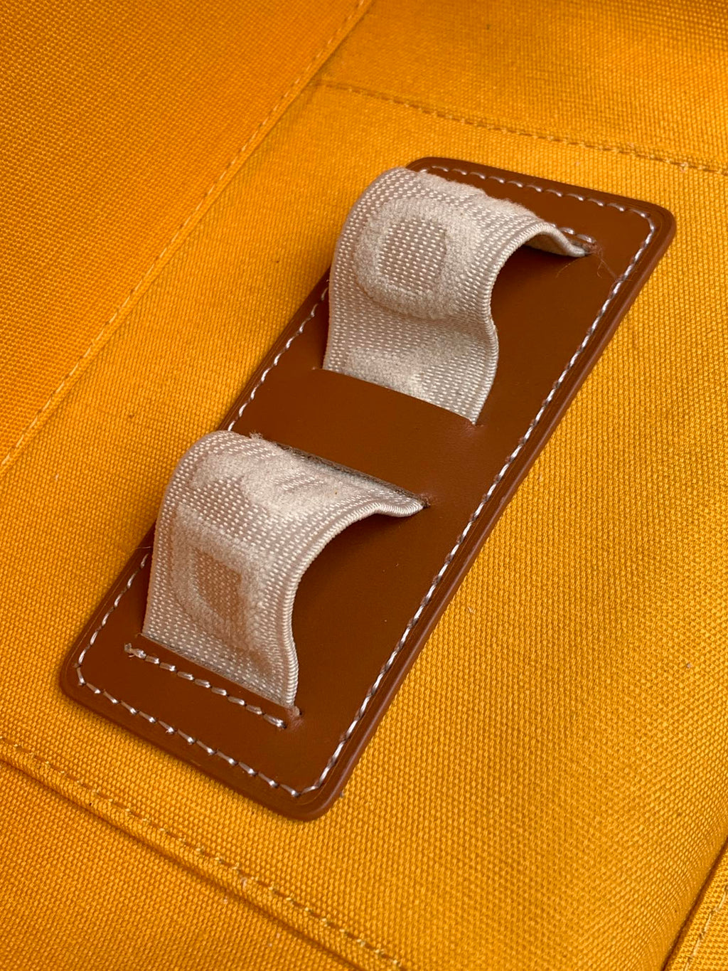 Goyard orange canvas bag with two fabric pull tabs and brown stitched pocket panel