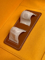Goyard orange canvas bag with two fabric pull tabs and brown stitched pocket panel
