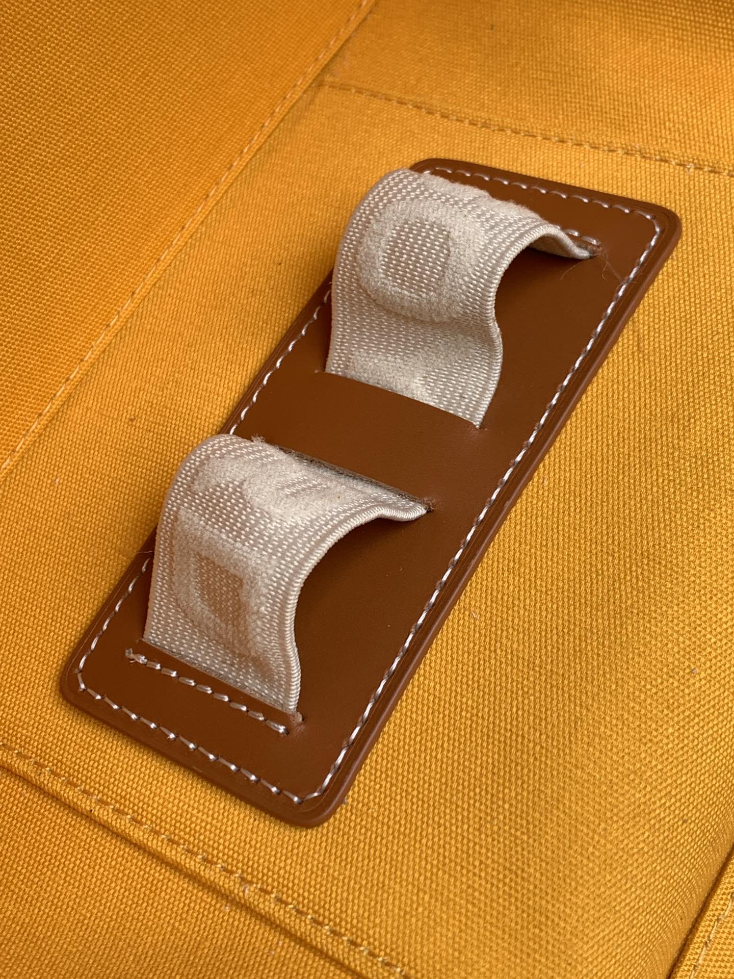 Goyard orange canvas bag with two fabric pull tabs and brown stitched pocket panel