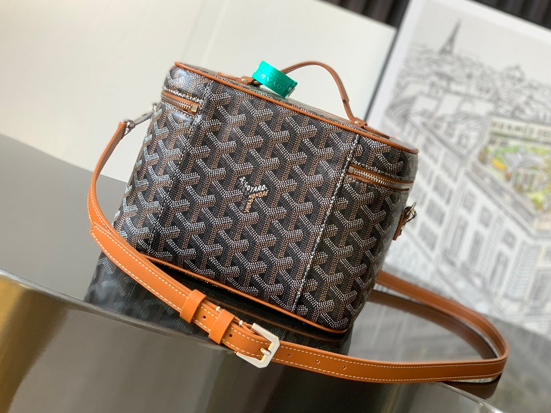 Small crossbody bag with tan leather strap and Goyard-print canvas; top zip and trim.
