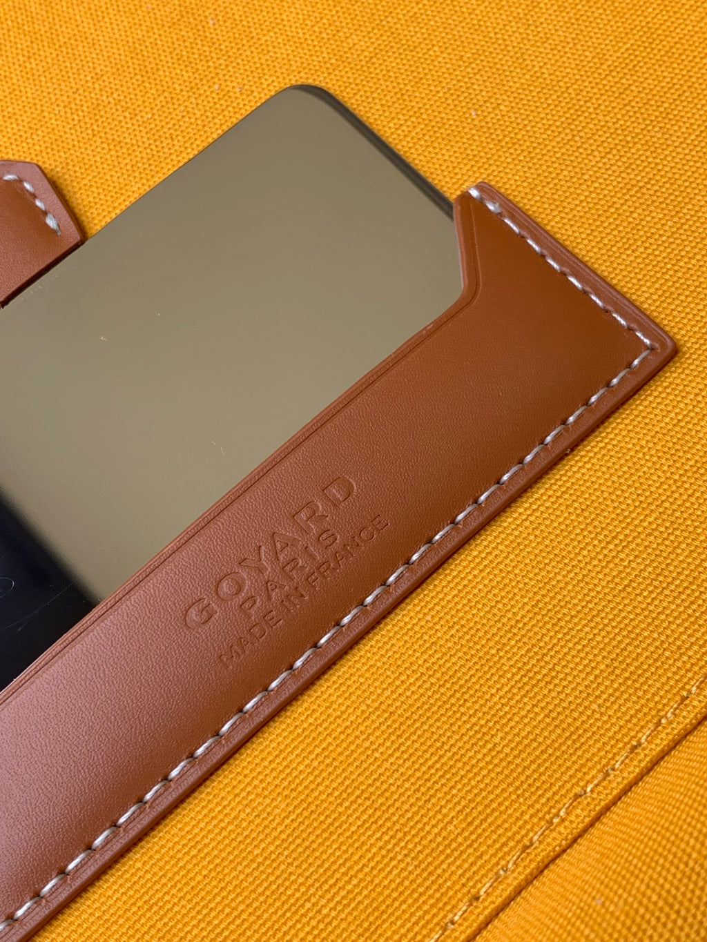 Small crossbody bag detail: tan leather flap with embossed GOYARD logo.